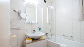 Une salle de bain moderne avec un lavabo blanc, un miroir et une douche.