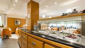 A buffet area with various food stations, a wooden counter, and a seating area with tables and chairs. - Relais San Giusto (Campitello di Fassa)