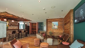Un interior moderno con una zona de bar, asientos y una pantalla de televisión que muestra un menú.