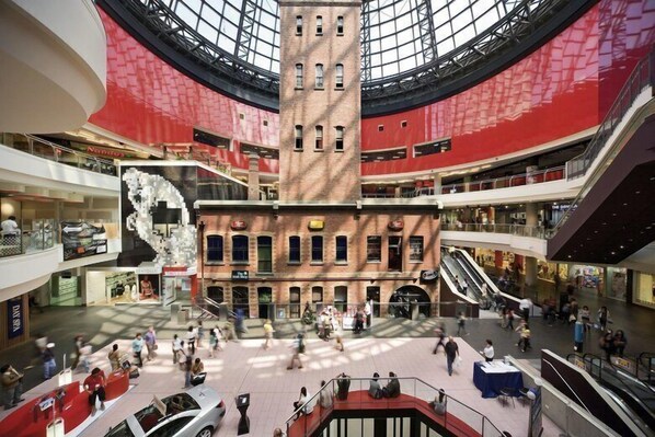 Un centro comercial de varios niveles con un atrio central, escaleras mecánicas y diversas tiendas.