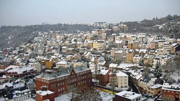 A densely packed urban area with snow-covered buildings and a hilly backdrop.
