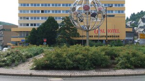 Um edifício de hotel com uma placa que diz "OPAL HOTEL" e uma escultura esférica na frente.
