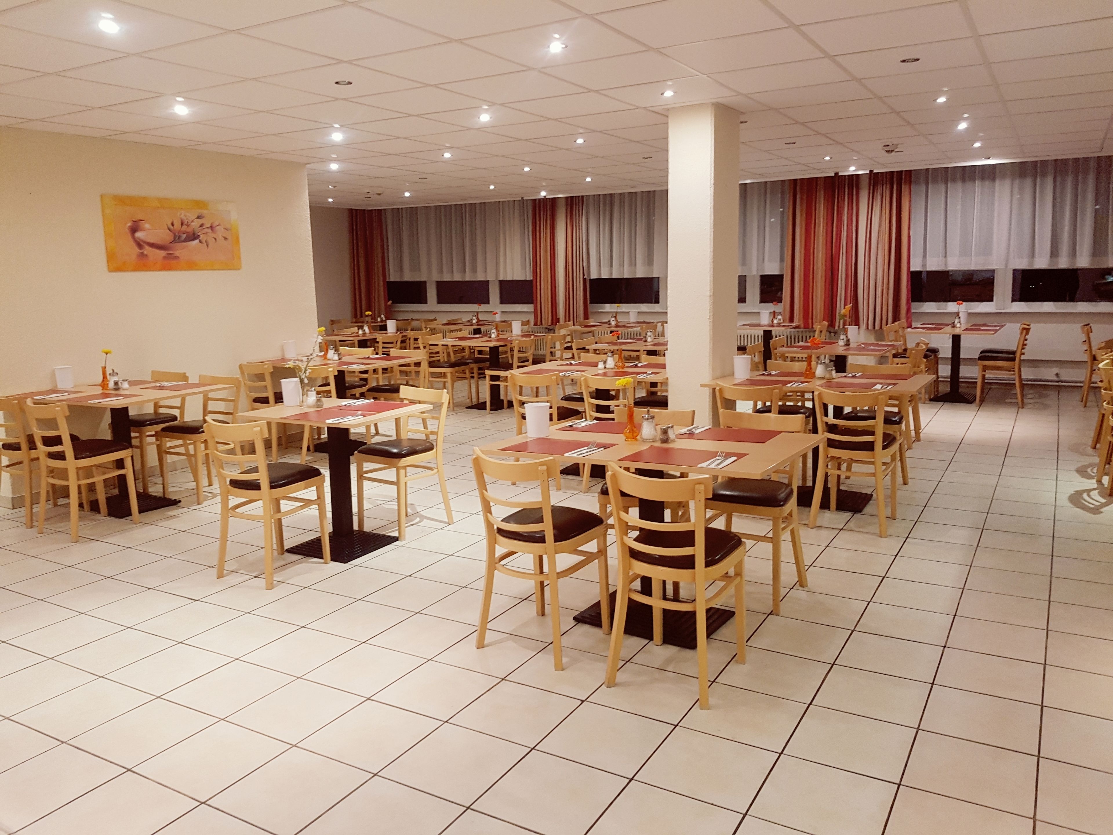 A spacious dining area with multiple tables and chairs, arranged in rows.