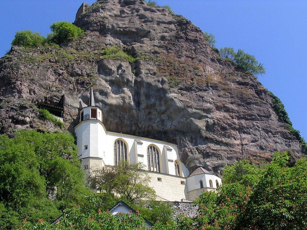 Une église dotée d’un clocher et d’une grande formation rocheuse en arrière-plan.