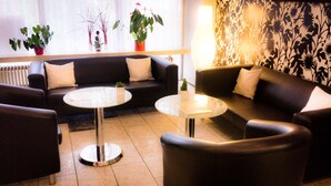 Uma sala de estar moderna com um sofá, duas mesas redondas e plantas decorativas.