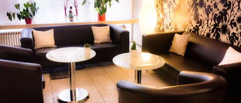 A modern living room with a sofa, two round tables, and decorative plants.