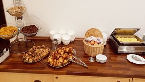 Buffet com diversos alimentos, incluindo doces, frutas e um espaço para café.