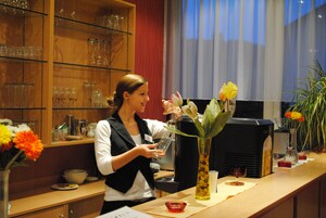 Una mujer en la barra, con un jarrón de flores, una copa y un menú.
