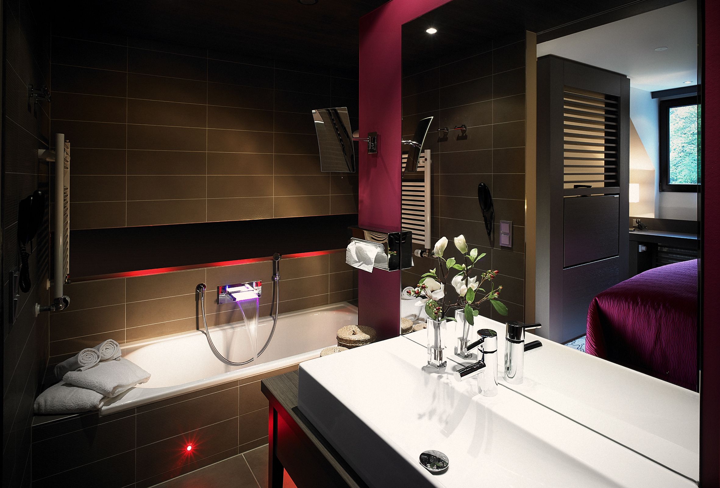 A modern bathroom with a bathtub, a vanity with a mirror, and a shower area.