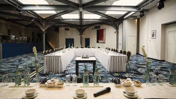 Ein Konferenzraum mit einem langen Tisch, der für ein Meeting vorbereitet ist, ausgestattet mit Wasserflaschen, Gläsern und einem Projektor.