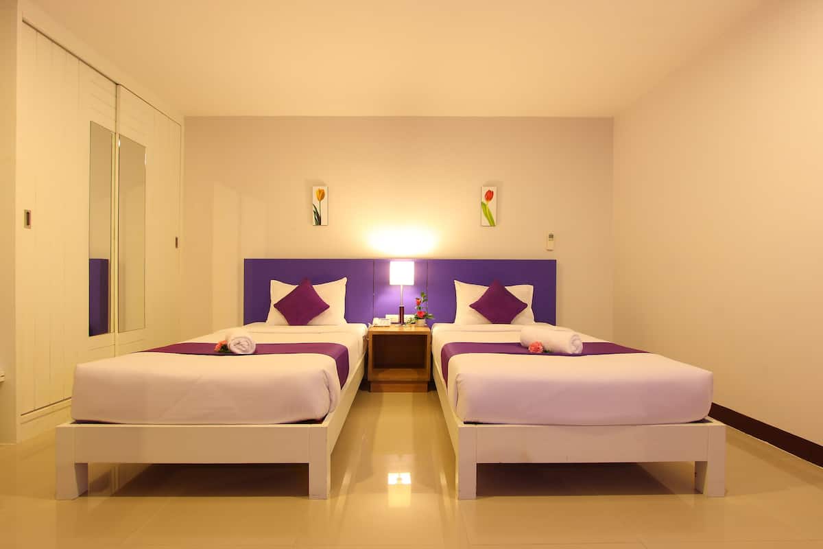 Een hotelkamer met twee bedden, een nachtkastje en een spiegel.