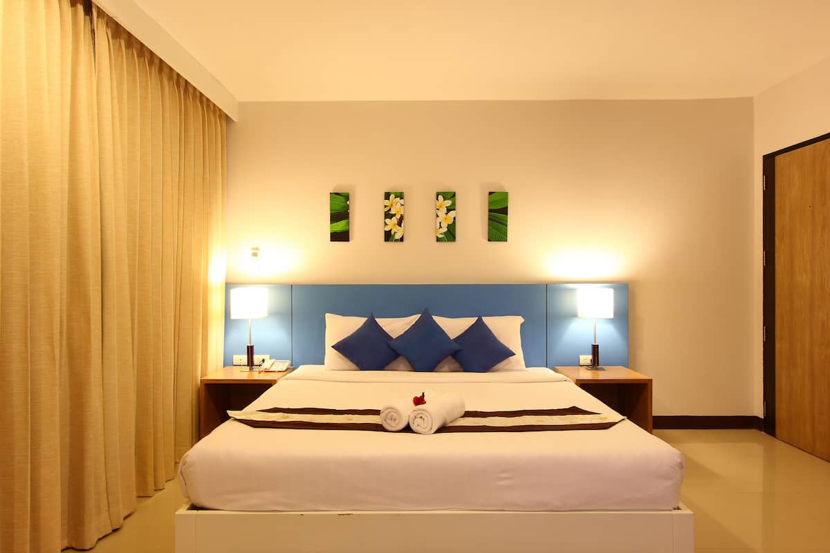 Een hotelkamer met een groot bed, twee nachtkastjes, een hoofdbord en een aan de muur bevestigd kunstwerk.