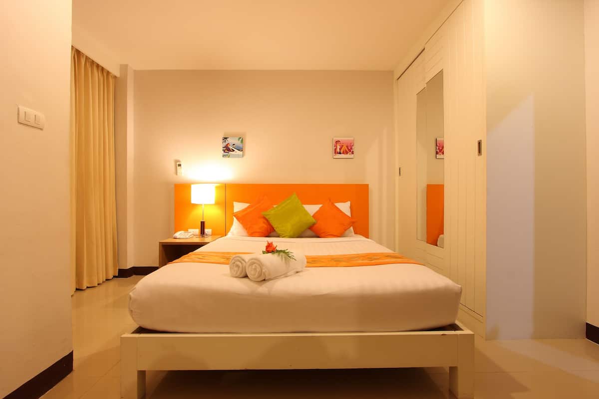 Een hotelkamer met een bed, nachtkastje, lamp en spiegel.