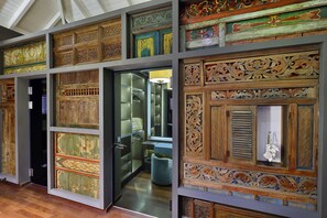 A room with ornate wooden panels and a glass door leading to a bathroom.