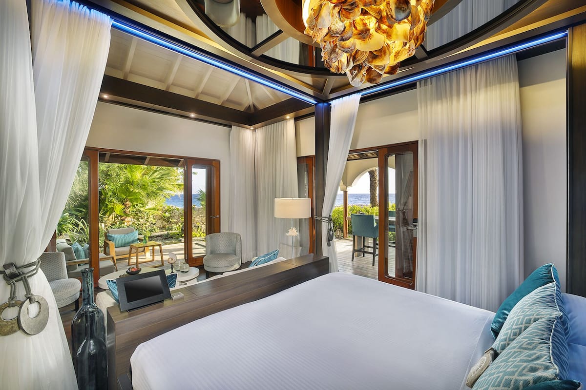 A spacious bedroom with a large bed, a view of the outdoors, and a ceiling with a unique shell design.