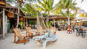 A beachside restaurant with wooden chairs, a large table, and a boat sculpture.