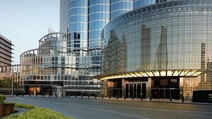 A modern hotel with a curved glass facade, large windows, and a well-lit entrance.