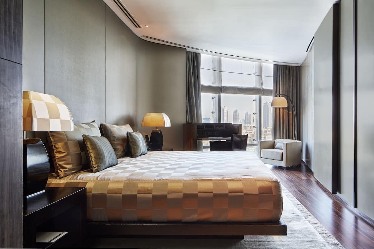 Ein modernes Hotelzimmer mit einem großen Bett, zwei Nachttischen, einem Fernseher und Blick auf die Stadt.