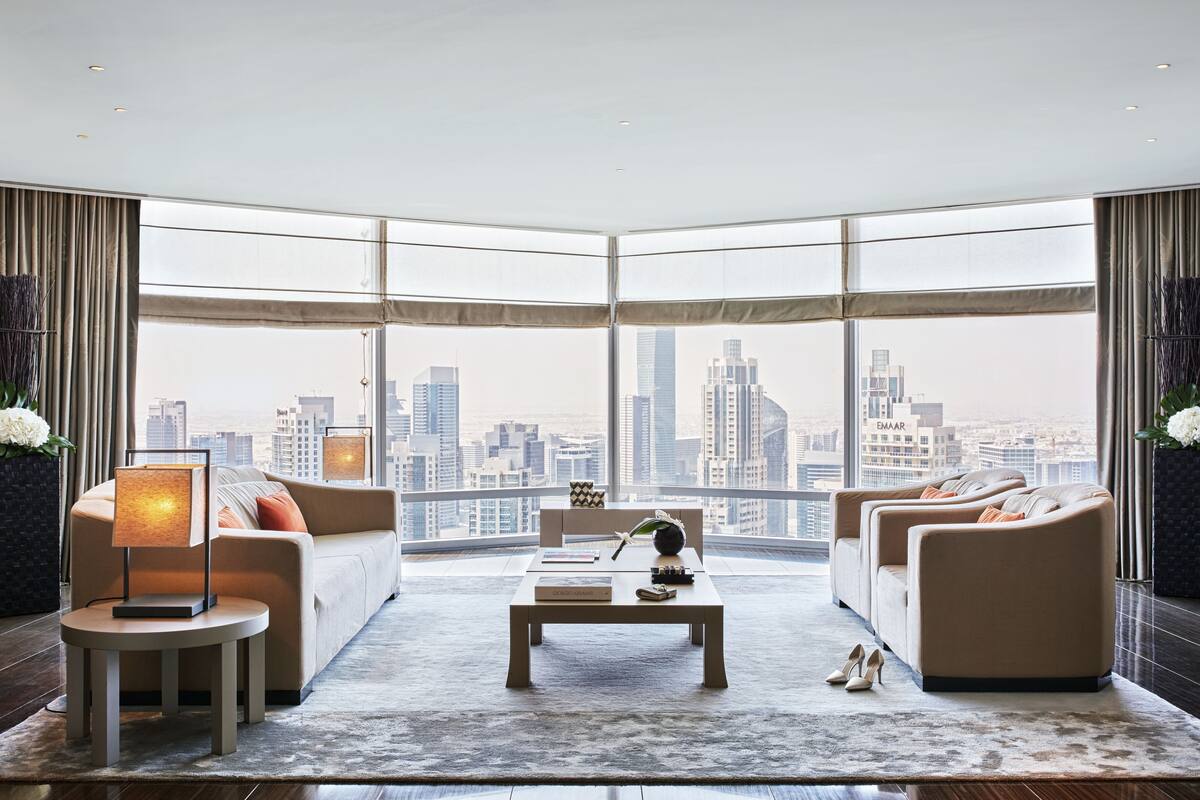 Ein modernes Wohnzimmer mit Blick auf die Stadt, ausgestattet mit einer Sofagarnitur, einem Couchtisch und einer Lampe.