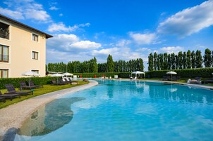 Una piscina al aire libre de temporada, sombrillas, tumbonas