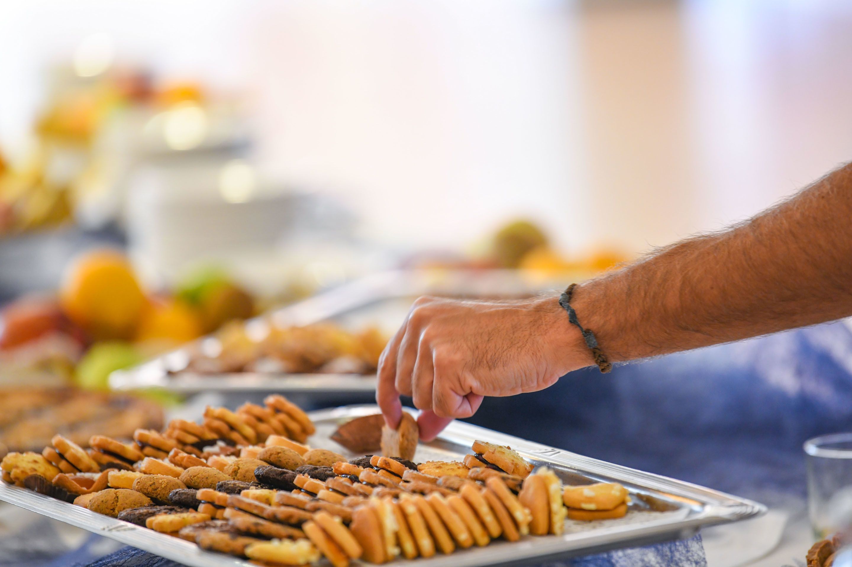 A tray of assorted snacks with a hand reaching for one.
