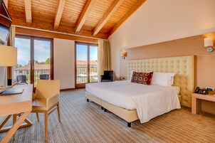 Una habitación de hotel con una cama grande, un escritorio y una silla. Se ve una ventana con vistas a edificios.