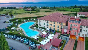 A hotel with a swimming pool, outdoor seating, and a view of the mountains. - TH Lazise - Hotel Parchi del Garda (Lazise)