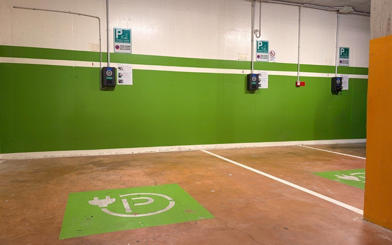 Un parking avec des murs végétalisés, de nombreuses places de stationnement et des bornes de recharge pour véhicules électriques.