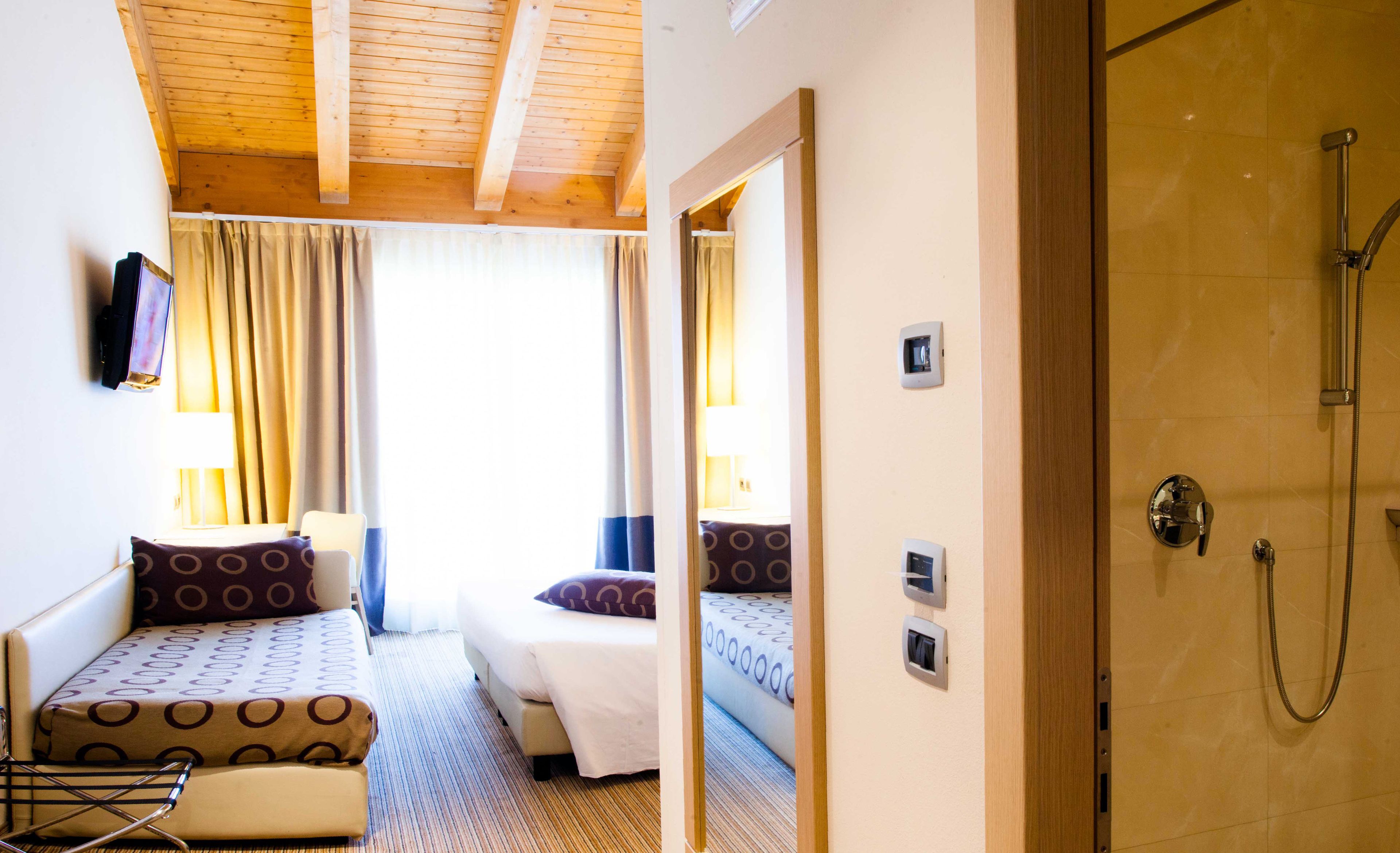 Ein Hotelzimmer mit zwei Betten, einer Dusche und einem Spiegel, der den Raum widerspiegelt.
