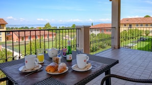 A balcony with breakfast items, including croissants, coffee, and juice, overlooking a scenic view of buildings and greenery. - TH Lazise - Hotel Parchi del Garda (Lazise)