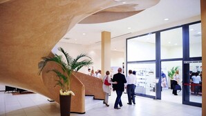 A modern lobby with a curved wall, a reception desk, and a large potted plant. - TH Lazise - Hotel Parchi del Garda (Lazise)