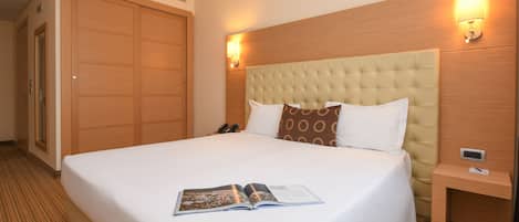 Une chambre d’hôtel avec un grand lit, une tête de lit en bois, deux lampes de chevet et une table de chevet.