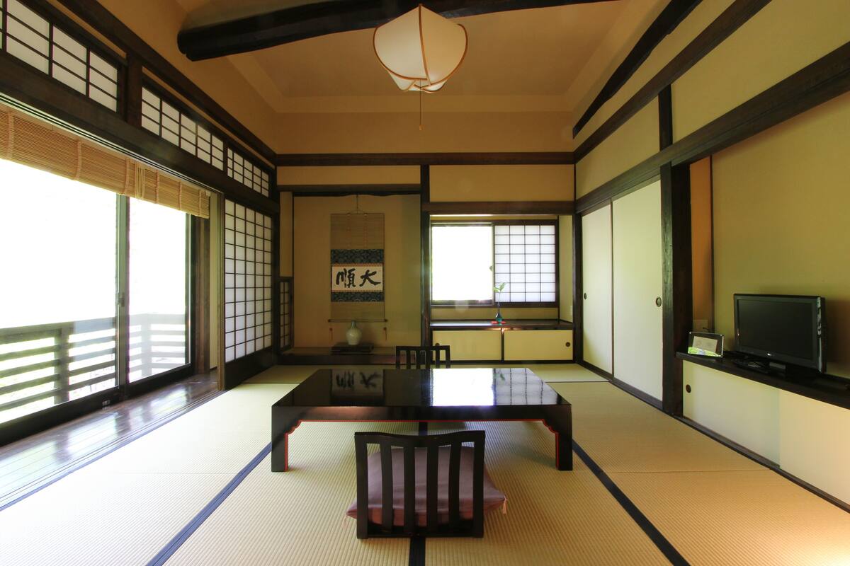 Una habitación tradicional japonesa con suelo de tatami, una mesa baja y puertas correderas.