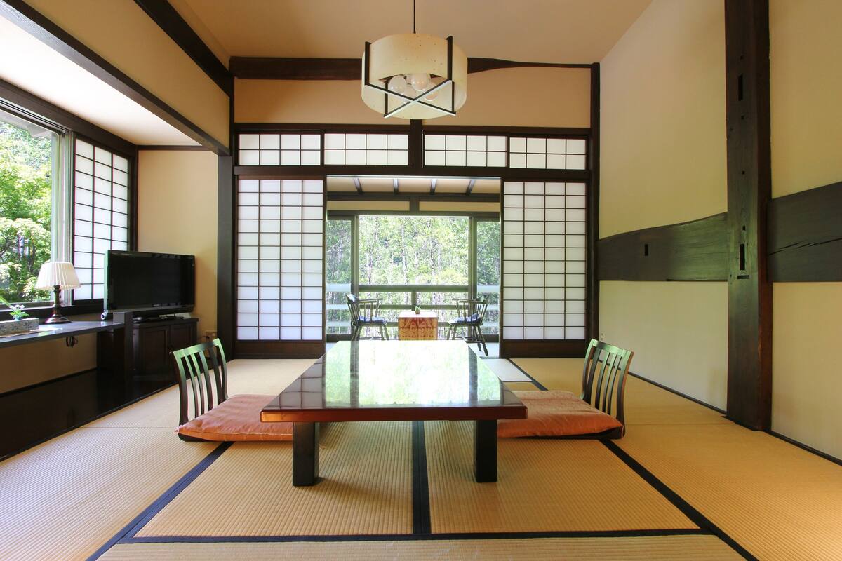 Una habitación japonesa tradicional con suelo de tatami, una mesa baja y puertas correderas.
