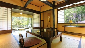 Una habitación japonesa tradicional con suelo de tatami, una mesa baja y puertas correderas.