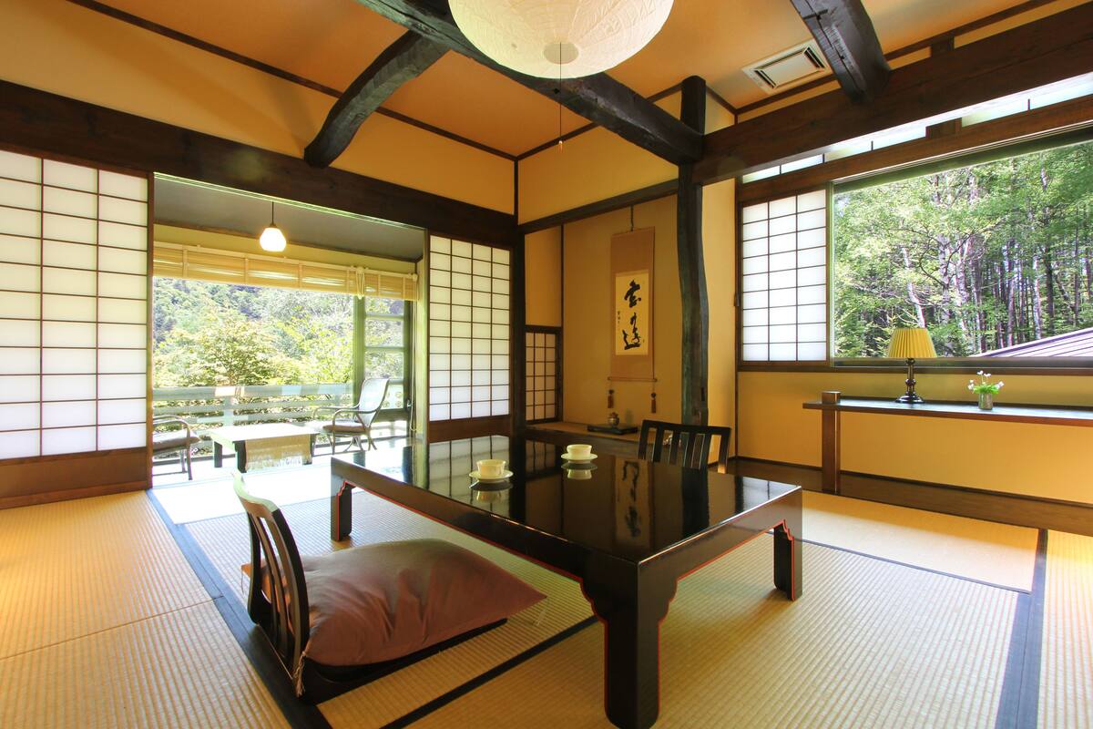 Una habitación japonesa tradicional con suelo de tatami, una mesa baja y puertas correderas.