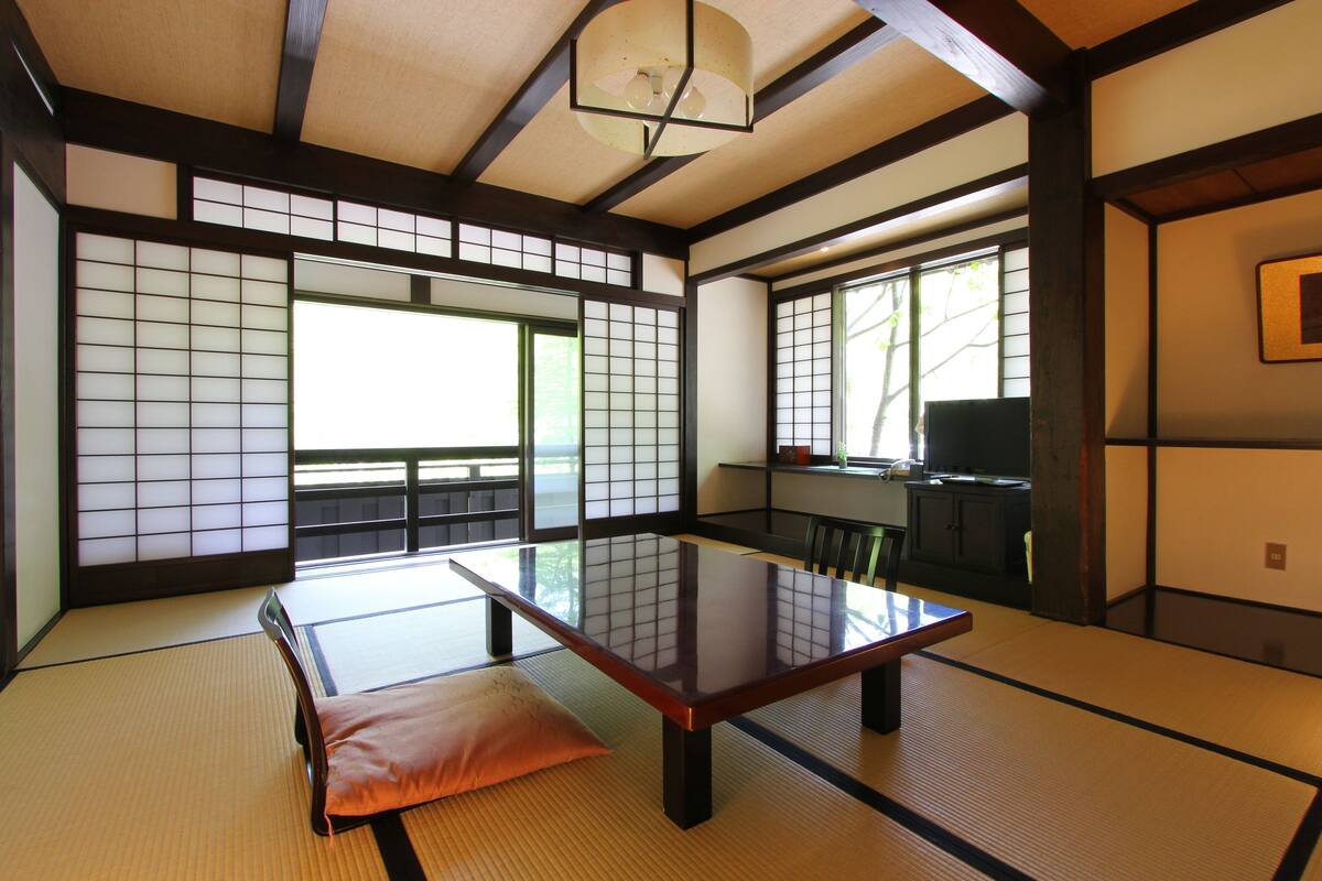 Una habitación japonesa tradicional con suelo de tatami, una mesa baja y puertas correderas shoji.