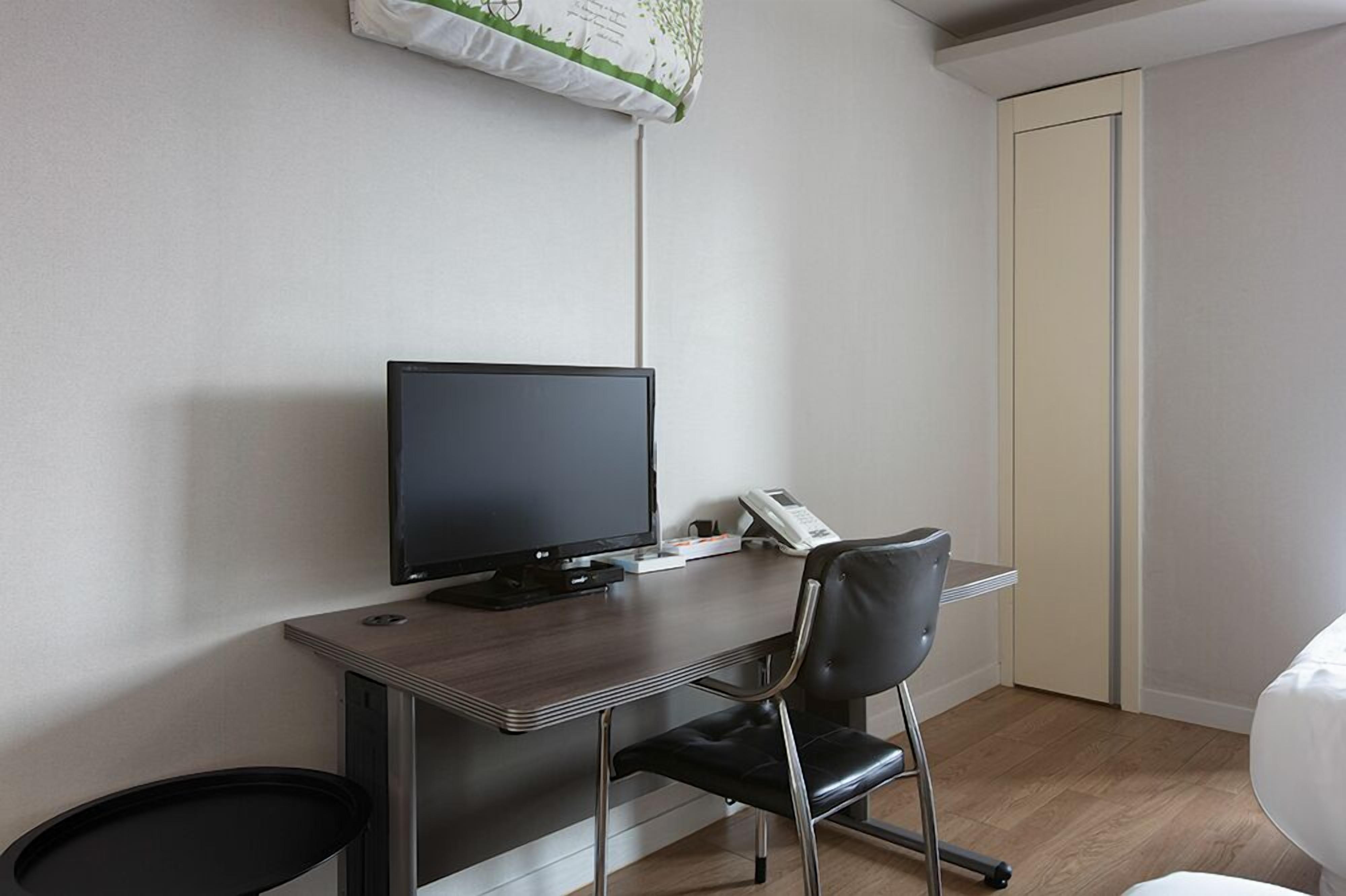 Un espacio de oficina moderno con un escritorio, un monitor de computadora, un teléfono y una silla.