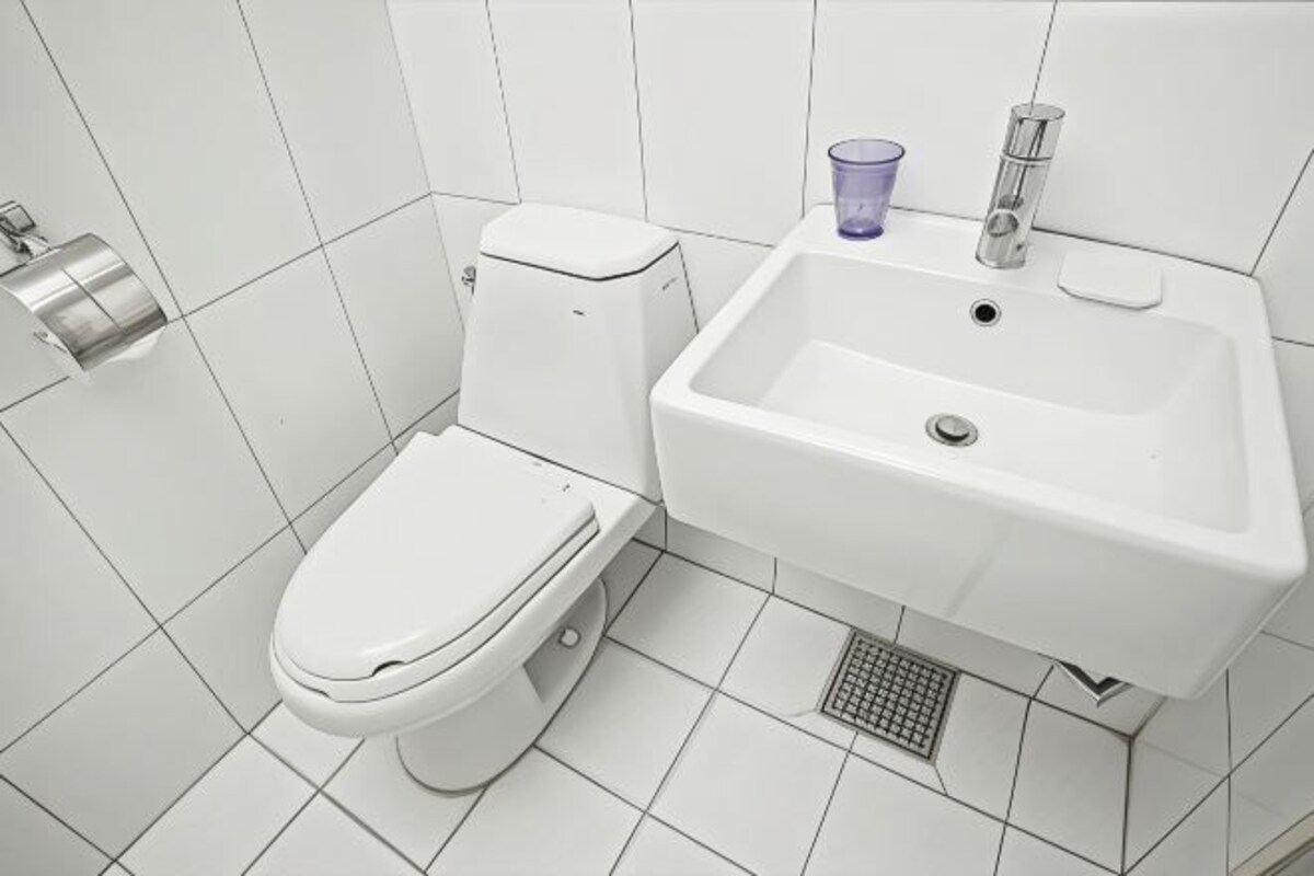 A modern bathroom with a toilet, sink, and a toilet paper holder.