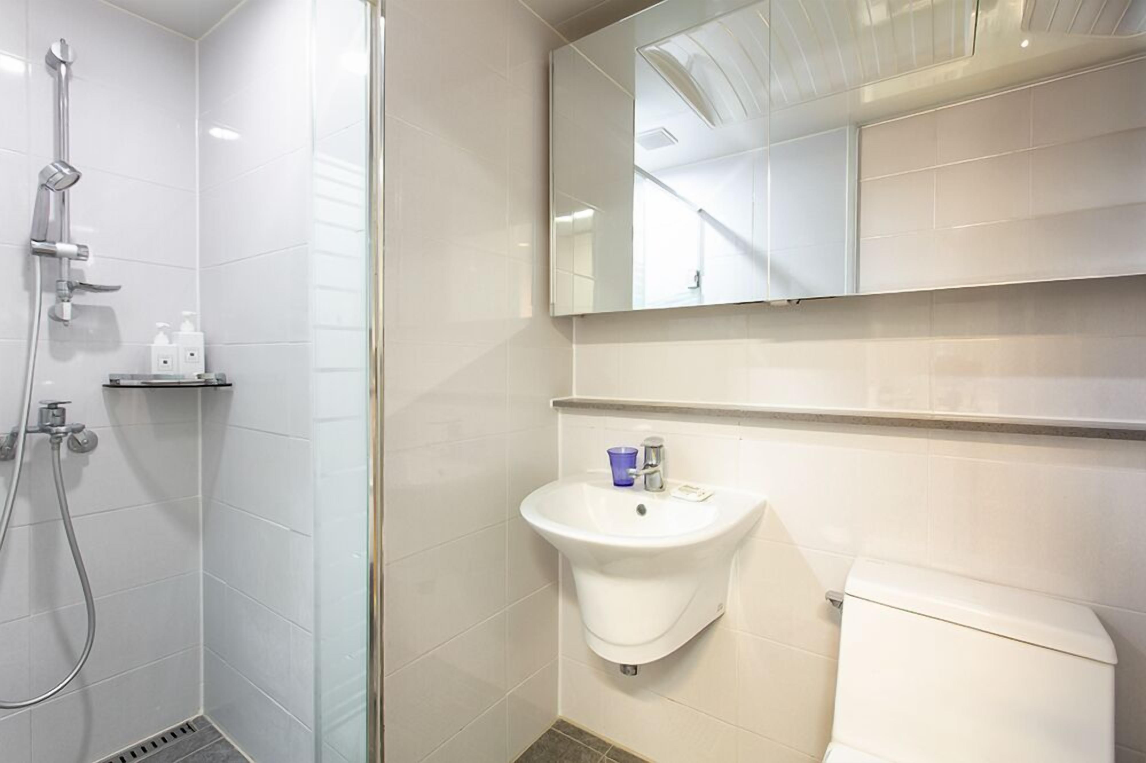 A modern bathroom with a shower, sink, and toilet.