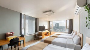 Une chambre d’hôtel avec deux lits, un bureau, une chaise, une télévision et une fenêtre donnant sur la ville.
