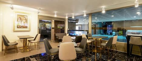 A modern hotel lobby with marble flooring, contemporary furniture, and a view of the airport through large windows.
