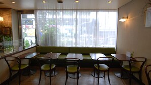 A restaurant interior with a green sofa, wooden tables, and chairs. - Hotel New Star Ikebukuro (Tokyo)