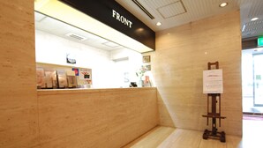 A reception area with a wooden counter, a sign reading "FRONT", and a small easel with a notice. - Hotel New Star Ikebukuro (Tokyo)