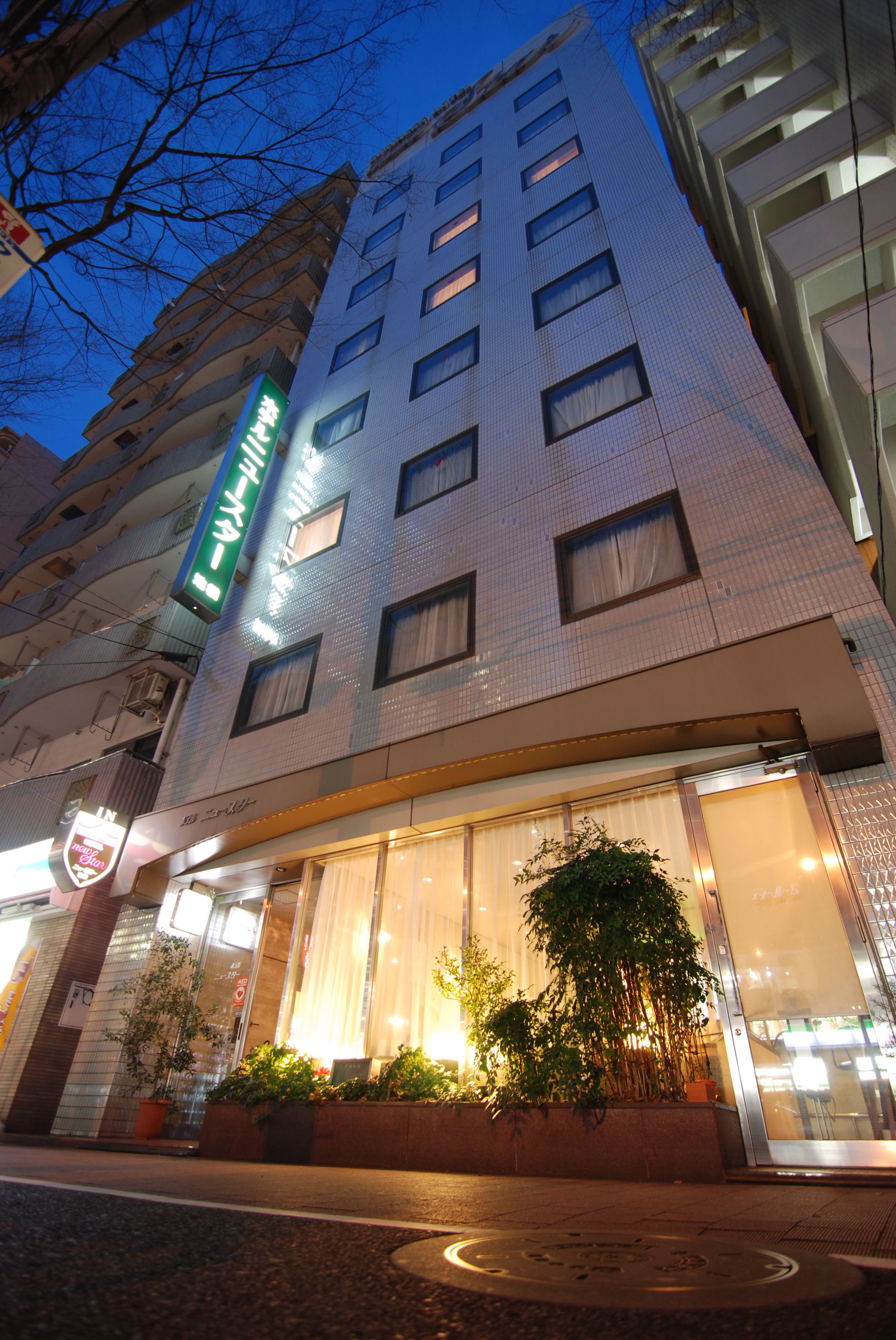 A hotel with a modern facade, large windows, and a green sign indicating it is a hotel.