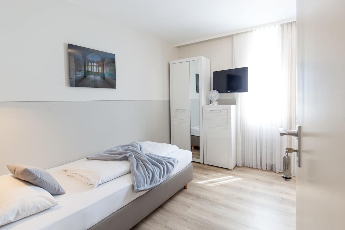 Une chambre à coucher moderne, équipée d’un lit, d’un téléviseur à écran plat, d’un miroir et d’une porte.