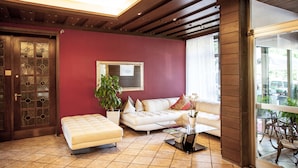 Ein Wohnzimmer mit einem weißen Sofa, einem Glastisch, einem Blumentopf und einer Holztür mit Glasfeldern.