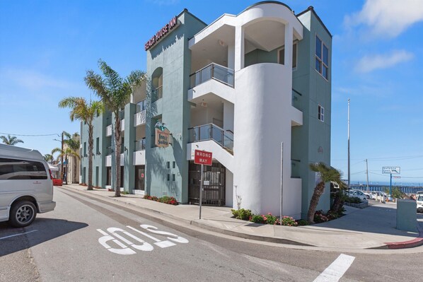 Un hôtel à plusieurs étages, doté d’une façade incurvée, d’une enseigne indiquant « Beach House Inn » et d’un panneau « Sens interdit ».