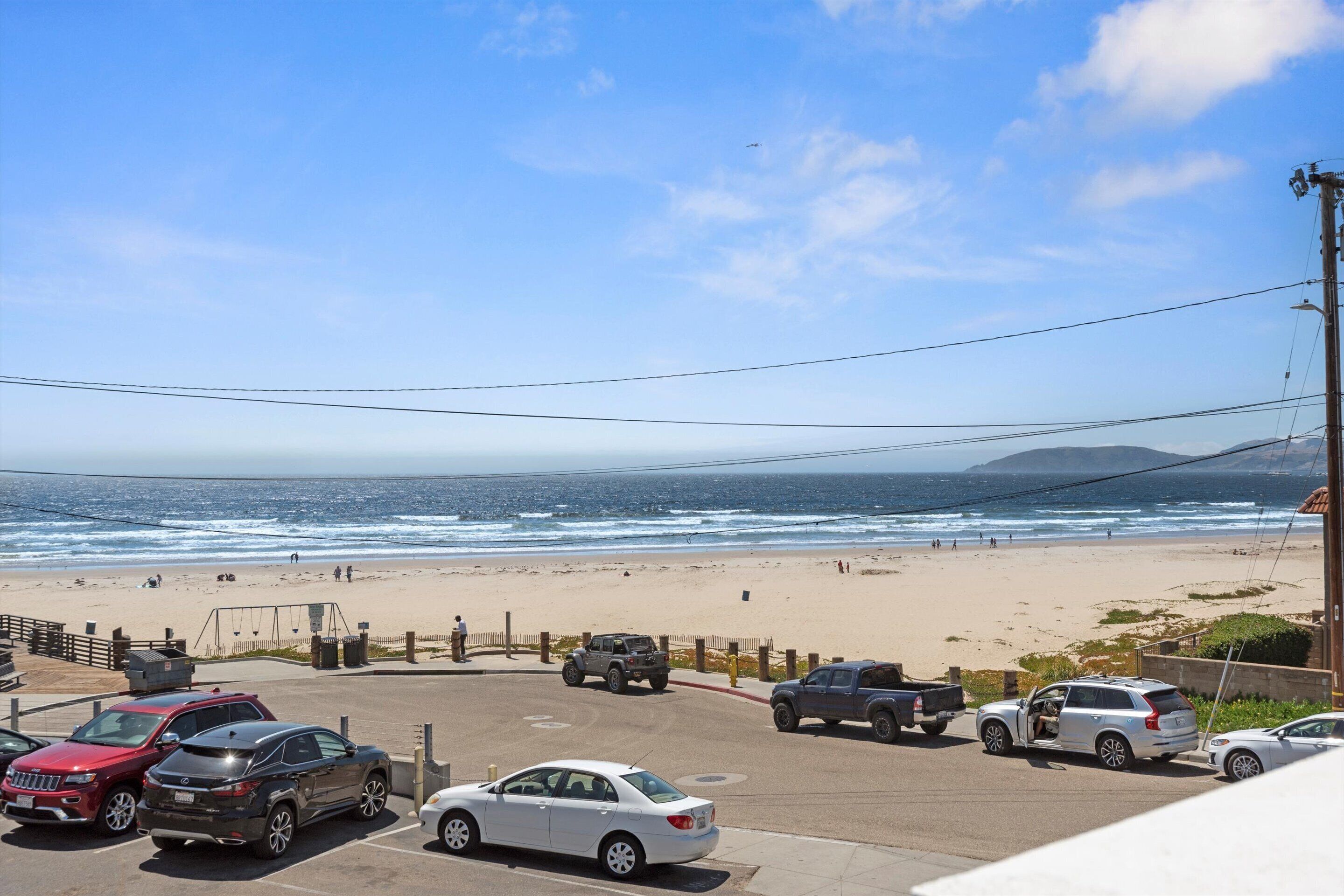Un estacionamiento con coches y vista al mar.