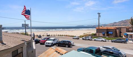 Vista de un estacionamiento frente al mar con varios coches, un letrero de motel y una bandera estadounidense.